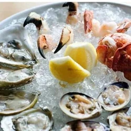 A chilled raw bar tower of oysters, clams, shrimp, and crab claws on ice with lemon at FISH Restaurant